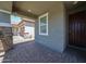 Covered front porch with stone pillars and brick flooring offers a charming welcome to the home at 10036 E Naranja Ave, Mesa, AZ 85209