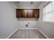 A laundry room with wood-look floors, upper cabinets, a window, and washer/dryer hookups at 10036 E Naranja Ave, Mesa, AZ 85209