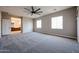 A large carpeted main bedroom with a ceiling fan, neutral paint, and access to the bathroom at 10036 E Naranja Ave, Mesa, AZ 85209