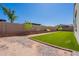 Landscaped backyard featuring artificial turf, decorative rock, and brick accents, enclosed by a block wall at 10348 E Tupelo Ave, Mesa, AZ 85212