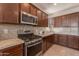 Well-lit kitchen with stainless steel appliances, granite countertops, and dark wood cabinets at 10348 E Tupelo Ave, Mesa, AZ 85212
