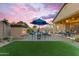 Backyard with a cozy fireplace, patio seating, and green artificial turf, creating a relaxing outdoor space at 10650 E Palladium Dr, Mesa, AZ 85212