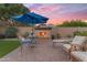 Inviting backyard featuring a cozy fireplace, comfortable seating, and lush green turf at 10650 E Palladium Dr, Mesa, AZ 85212