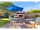 Inviting backyard seating area features a cozy fireplace and comfortable seating under a bright blue umbrella at 10650 E Palladium Dr, Mesa, AZ 85212