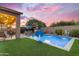 Backyard oasis featuring a sparkling pool with fountains and a playful basketball hoop under a vibrant sunset at 10650 E Palladium Dr, Mesa, AZ 85212