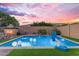 Evening shot of a gorgeous pool with colorful lights, fountain features, and a built-in fireplace for outdoor enjoyment at 10650 E Palladium Dr, Mesa, AZ 85212