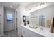 Bright bathroom with double sinks, white cabinets, and a large mirror at 13244 N 146Th Ln, Surprise, AZ 85379