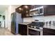 Close-up of kitchen area featuring stainless steel appliances, dark wood cabinetry, and granite countertops at 14338 W Bronco Trl, Surprise, AZ 85387