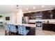 Open kitchen with stainless steel appliances, granite countertops, dark cabinets, and an island with breakfast bar seating at 14338 W Bronco Trl, Surprise, AZ 85387