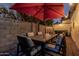 Outdoor dining area with seating for six, overhead lighting, and a large red umbrella for shade at 1522 W Willetta St, Phoenix, AZ 85007