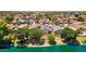 Homes with solar panels seen from above, bordering a picturesque lake with mature trees at 17115 N Larkspur Ln, Surprise, AZ 85374
