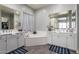 Bright bathroom featuring double vanity sinks with white cabinets, a soaking tub, and neutral gray walls at 18474 W College Dr, Goodyear, AZ 85395