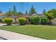 Charming single-story home featuring a well-manicured lawn, mature trees, and a two-car garage with a light brown roof at 2053 W Natal Cir, Mesa, AZ 85202