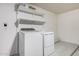 Clean laundry room with a white washer and dryer, white shelves, and a concrete floor at 3343 W Lone Cacuts Dr, Phoenix, AZ 85027