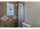 Modern bathroom shower featuring glass block window, white toilet, and tiled walls for easy cleaning at 3347 W Roma Ave, Phoenix, AZ 85017