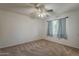 Bright bedroom with neutral carpet, ceiling fan, and a window with curtains for privacy and light control at 3347 W Roma Ave, Phoenix, AZ 85017