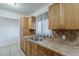 Bright kitchen showcasing wood cabinets, tile backsplash, stainless steel sink, and a window with curtains at 3347 W Roma Ave, Phoenix, AZ 85017