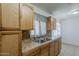 Kitchen sink with wood cabinets, tile backsplash, stainless steel sink, and a window with drapes at 3347 W Roma Ave, Phoenix, AZ 85017