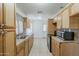 Galley kitchen features wood cabinets, tile backsplash, stainless steel sink, and tile flooring at 3347 W Roma Ave, Phoenix, AZ 85017