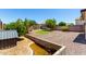 Landscaped backyard with grass, trees, a water feature, and a retaining wall at 40316 W Hopper Dr, Maricopa, AZ 85138