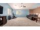 Spacious bonus room featuring a ceiling fan, exercise bike, large windows and a sofa at 40316 W Hopper Dr, Maricopa, AZ 85138