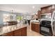 Open kitchen boasts stainless steel appliances, tiled floor, dark cabinets and an adjacent dining area at 40316 W Hopper Dr, Maricopa, AZ 85138