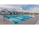 Community pool featuring lap lanes, shaded seating, and mountain views under a partly cloudy blue sky at 4067 W Maggie Dr, San Tan Valley, AZ 85144