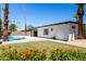 Landscaped backyard with a pool, lush green lawn, and colorful flowers, creating a serene and inviting outdoor space at 5211 E Winchcomb Dr, Scottsdale, AZ 85254