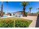Spacious backyard featuring a pool, lawn, colorful flowers, and mature palm trees creating a private oasis at 5211 E Winchcomb Dr, Scottsdale, AZ 85254