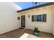 Covered porch with gravel landscaping and blue planter with colorful annuals by a black door at 5211 E Winchcomb Dr, Scottsdale, AZ 85254