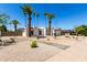 Charming white home with desert landscaping, red tiled roof and numerous palm trees at 5211 E Winchcomb Dr, Scottsdale, AZ 85254