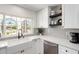 Updated kitchen featuring a farmhouse sink, stainless steel dishwasher, modern backsplash, and white cabinets at 5211 E Winchcomb Dr, Scottsdale, AZ 85254