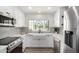 Bright updated kitchen boasts white cabinetry, stainless appliances, white farmhouse sink and decorative tile backsplash at 5211 E Winchcomb Dr, Scottsdale, AZ 85254
