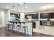 Open kitchen with an island bar, dark wood cabinetry, tile and wood flooring, and stainless appliances at 5243 E Windstone Trl, Cave Creek, AZ 85331