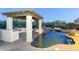 An outdoor swimming pool with waterfall and covered area featuring a built-in grill at 5243 E Windstone Trl, Cave Creek, AZ 85331