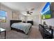 This bright main bedroom offers neutral walls, a ceiling fan, and a big screen TV at 5805 W Warner St, Phoenix, AZ 85043