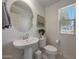 Bright powder room with pedestal sink, round mirror, a toilet, artwork, and natural light at 5805 W Warner St, Phoenix, AZ 85043