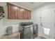 Functional laundry room with dark cabinetry, modern washer and dryer, and an exterior door at 643 N 92Nd Pl, Mesa, AZ 85207