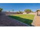 Manicured backyard features green grass, gravel, and a block wall with mature trees at 656 E Mesquite Ave, Apache Junction, AZ 85119