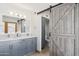 Bathroom with a double sink vanity, grey cabinets, and sliding barn door at 7036 E Sheena Dr, Scottsdale, AZ 85254