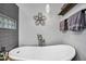 Bright bathroom featuring soaking tub, gray tiling, and designer light fixture at 7202 N 16Th Dr, Phoenix, AZ 85021