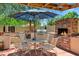 Outdoor kitchen with brick fireplace, built in BBQ, and dining area, great for entertainment in a backyard oasis at 7202 N 16Th Dr, Phoenix, AZ 85021
