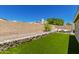 Large backyard with artificial grass, rock borders, and comfortable seating area at 902 E Wahalla Ln, Phoenix, AZ 85024