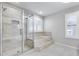 Bright bathroom featuring a glass enclosed shower, a tub with tile surround, and shuttered windows at 11217 E Laurel Ln, Scottsdale, AZ 85259