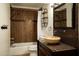 Bathroom featuring warm wood tile, decorative mirror, shelving, and vessel sink on a dark wood vanity at 13034 N 8Th Ave, Phoenix, AZ 85029