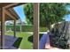 Backyard view featuring artificial grass, lush tree, manicured shrubs, and covered patio at 1417 E Marshall Ave, Phoenix, AZ 85014