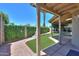 View of backyard featuring an artificial grass lawn, gravel borders, covered patio, and manicured hedges at 1417 E Marshall Ave, Phoenix, AZ 85014