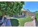 Backyard view featuring an artificial grass lawn, stone water feature, covered patio, and landscaping at 1417 E Marshall Ave, Phoenix, AZ 85014