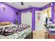 A bedroom with purple walls, white closets and door, as well as a gaming chair and bedding at 1619 E Aspen Ave, Buckeye, AZ 85326