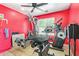 This bright red exercise room has multiple machines, tiled floors and a ceiling fan at 1619 E Aspen Ave, Buckeye, AZ 85326